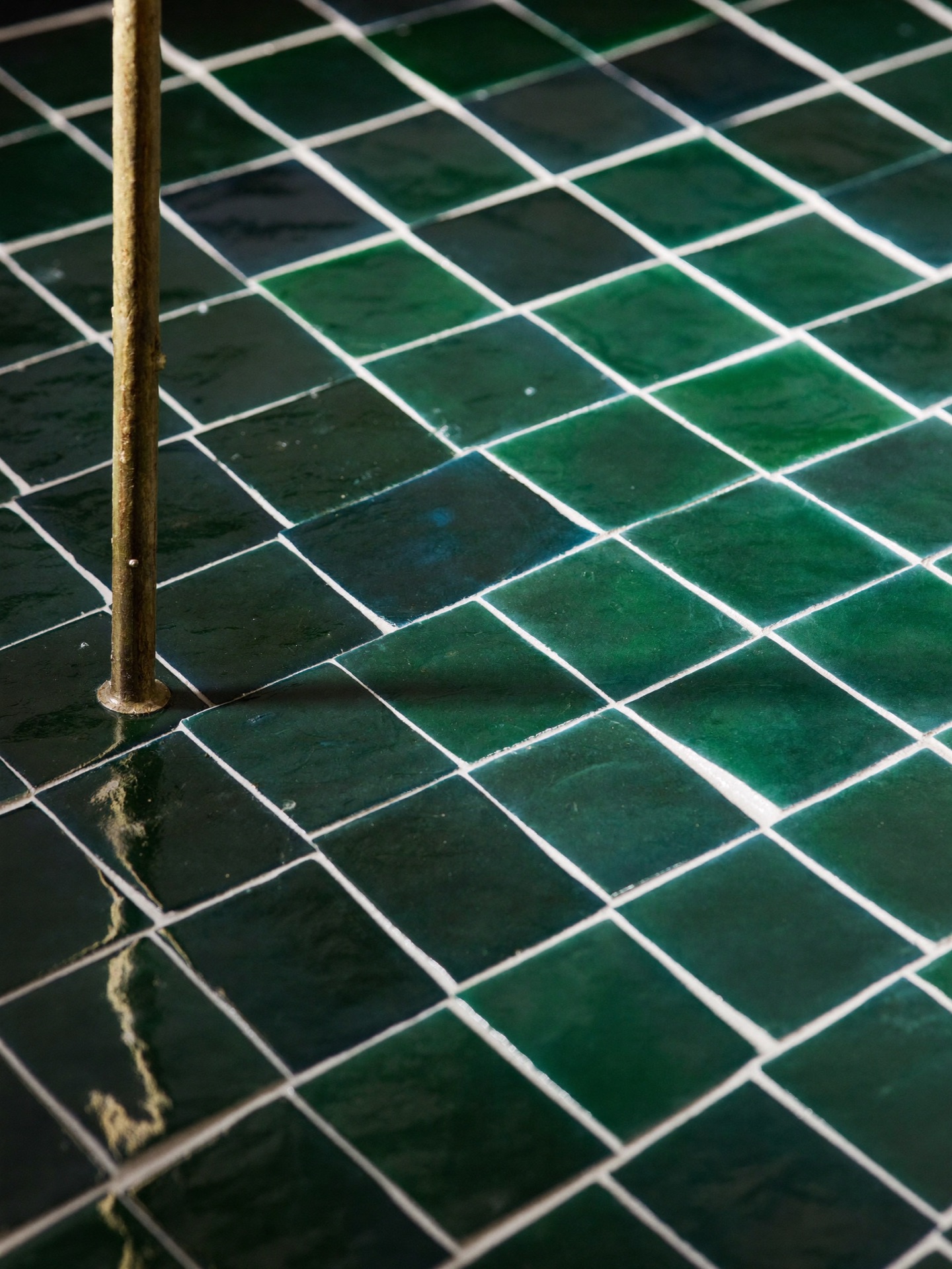 Macro of glazed green zellige tile, each piece slightly uneven, catching warm light on a Scottsdale bath wall